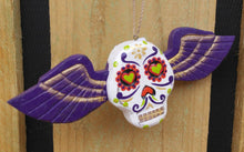 Load image into Gallery viewer, Hanging wooden skull with purple wings.
