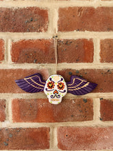 Load image into Gallery viewer, Hanging wooden skull with purple wings.
